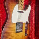 Elektrická kytara typu Telecaster s tělem z vyzréného dřeva s výraznou žluto-hnědou strukturou a bílým pickguardem. Nástroj má javorový hmatník a je…