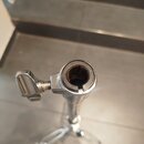 Detailní pohled na horní část chromovaného stojanu s utahovacím šroubem a knoflíkem. V horní části je kulatý otvor s černou gumovou vložkou, která vy…