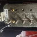 Elektrický snímač s kovovým krytem stříbrné barvy. Na povrchu je vyražen nápis „Seymour Duncan“ a pod ním menší text „Made in america“. Na boku je př…