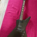 Černá elektrická kytara s matným povrchem a atypickým, ostře hranatým tvarem korpusu. Hmatník obsahuje bílé ozdobné vkládky ve tvaru křížů. Na hlavě…