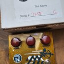 Krabice a kytarový efekt pedál značky RYRA. Na krabici je nápis „RYRA Quality Sound Gear“, model „The Klone“ a ručně zapsané sériové číslo „Serial #…