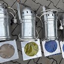 Čtyři stříbrné kovové reflektory s rukojetí a přívodními kabely. Každý reflektor má před sebou čtvercový rám s barevným filtrem v odstínech bílé, žlu…