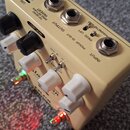 Béžový efekt pedál s bílými a černými oválnými knoflíky. Na horní straně jsou konektory s nápisy USB, DC 9V, INSER (TIP SEND RING RETURN), OUTPUT a I…