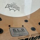 Detail dřevěného korpusu bubnu s bílýmI skinem značky REMO. Na korpusu je nalepený štítek s nápisy S.L.P., SOUND LAB PROJECT, Serial # 22090204, Hand…