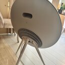 Šedý, kulatý reproduktor na třech dřevěných nohách. Na zadní straně je v horní části oválný úchop a ve spodní části mřížka ventilace. Žádné značky an…