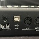 Detail zadní strany černého hudebního nástroje s řadou konektorů. Jsou zde čtyři vstupy pro pedály označené čísly 1, 2, 3 a 4 (Universal), jeden USB…
