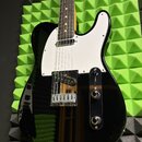 Černá elektrická kytara typu Telecaster s bílým pickguardem a hnědým hmatníkem. V pozici kobylkového snímače je umístěn humbucker s nápisem "Custom".…