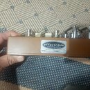 Hnědý efekt pedál s kovovým šasi a stříbrnými ovládacími prvky. Na boku je nalepený štítek s nápisem effectrode audiophile pedals, MODEL: 201 A a SER…