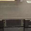 Černý rackový zesilovač s kovovým povrchem. Na předním panelu je vlevo nápis PSX1204D, uprostřed kontrolní panel s LED indikátory a vpravo logo BOSE…