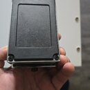 Fotografie zachycuje spodní stranu efektového pedálu v kovovém stříbrném provedení. Na spodku je připevněna velká černá protiskluzová gumová plocha.…