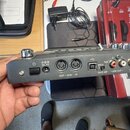 Fotografie zachycuje zadní panel stříbrného elektronického zařízení. Jsou zde vidět nápisy DC 9V, OUT - MIDI - IN, SPEED, TIME, GATE ARP, LINE OUT -…