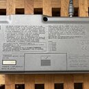 Záběr na zadní stranu šedého plastového elektronického zařízení. Na štítku je uveden nápis YAMAHA MODEL QY70 a sériové číslo NO 10654, dále YAMAHA CO…