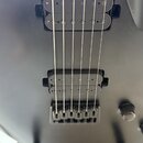 Detailní pohled na tělo elektrické kytary v matně černé barvě. Nástroj má dva humbuckery a fixační kobylku s pružinami. Na povrchu nejsou vidět žádné…