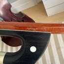 Detail krku smyčcového nástroje s hnědým lakem a černou podložkou. Na dřevě je vyryt nápis CZECH REPUBLIC. Povrch laku vykazuje drobné oděrky a známk…