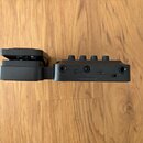 Černý kompaktní efekt pedál z plastu nebo kovu. Na bočním panelu jsou vidět konektory a nápisy: OUTPUT, USB 5V power, DC 9V, INPUT. Povrch je v dobré…