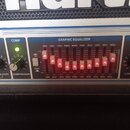 Detailní pohled na ovládací panel zesilovače s částí označenou jako GRAPHIC EQUALIZER. Equalizer obsahuje deset posuvníků s červenými kontrolkami a p…