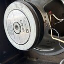 Fotografie zachycuje zadní část reproduktoru s kovovým magnetem a šedým rámem. Na stříbrném štítku je uveden nápis Celestion G12-80, impedance 8 ohms…