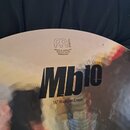 Detailní pohled na povrch činchy v zlatavé barvě. Na povrchu je vidět logo MEINL, nápisy MADE IN GERMANY, ROLAND MEINL a sériové číslo 190803857. Dom…