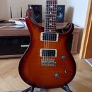 Elektrická kytara s hnědým gradientním lakem a dvěma humbuckery. Na krytech snímačů je viditelný nápis emg. Hmatník má bílé ozdobné vložky ve tvaru p…
