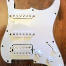 Bílá pickguard pro elektrickou kytaru s třemi snímači. Horní dva snímače jsou jednoduché (single-coil) a spodní je humbucker s dvěmi řadami pólů. Sou…