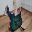 Elektrická kytara s modro-zeleným přechodem barvy na těle a světlým hmatníkem. Nástroj má dva humbuckery, jeden ovládací knoflík a přepínač. Kytara s…