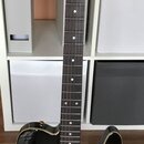 Černá elektrická kytara s matným povrchem a zlatými detaily. Na hlavě hmatníku je bílý nápis „Hardy Barton“ a menší text „Custom Series“. Nástroj má…