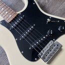Krémová elektrická kytara s černým pickguardem a hnedým hmatníkem. Nástroj má tři snímače typu single-coil, jeden ovládací knoflík s nápisem VOLUME a…