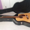 Akustická kytara s přirozenou dřevěnou barvou v černém tvrdém pouzdře. Na hmatníku je vidět nápis Fender. Nástroj vykazuje známky běžného používání,…