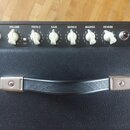 Horní panel černého kytarového komba s ovládacími prvky. Jsou zde nápisy INPUT, VOLUME, TREBLE, BASS, MIDDLE, MASTER a REVERB u bílých plastových kno…