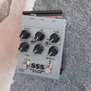 Šedý efekt pedál s kovovým krytem a šesti ovládacími knoflíky. Na přední straně je nápis SSS a pod ním text "STEEL STRING SUPREME". Nad knoflíky jsou…