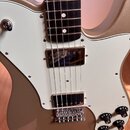 Elektrická kytara s kovově hnědým trupem a bílým pickguardem. Nástroj má dva chromované humbuckery, chromovaný kobylník a čtyři ovládací knofíky. Na…