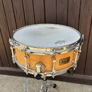 Dřevěný snare drum s přírodním povrchem a chromovaným kováním. Na blaně je viditelné logo REMO a na korpusu štítek s nápisem B.L.A. Custom Line Produ…