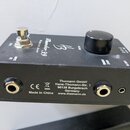 Černý kompaktní zesilovač s nápisy Thunder-99 a POWER AMP. Na horní straně se nachází stříbrný přepínač, černý ovládací knoflík a popisky MUTE, INPUT…