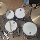 Celá bicí souprava v tmavě červeném provedení s kovovým hardwarem. Na činelech jsou vidět nápisy Zildjian, Anatolian a ULTIMATE. Na blbách a tom-tame…