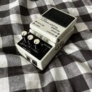Bílý efekt pedál s černým ovládacím panelem a bílými voličky. Na horní části je nápis BOSS Noise Suppressor NS-2. Na panelu jsou popisky INPUT, RETUR…