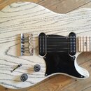 Elektrická kytara s tělem zC světlého dřeva s výraznou masivní kresbou. Nástroj má černý pickguard, dva snímače typu single-coil a jeden humbucker. N…