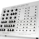 Bílý analogový syntetizátor v kovovém šasi s nápisem telemark na horní hraně. Přední panel obsahuje řadu potenciometrů, přepínačů a zapojovacích kone…