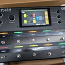Černý efektový procesor s nápisem HEADRUSH PEDALBOARD a logem Eleven HD EXPANDED. Zařízení má digitální displej, několik ovládacích knoflíků a dvě řa…