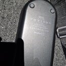 Fotografie zachycuje zadní stranu černého, plastového elektronického zařízení oválného tvaru. Na povrchu je vyraženo logo a nápis (Aliphonic INSTRUME…