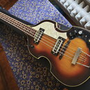 Elektrická basová kytara s trupem v barevném přechodu od tmavě hnědé po žlutou. Nástroj má bílý perleťový pickguard, dva snímače a tři ovládací knofl…