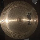 Zlatavý kovový činel s povrchem opatřeným klepanými důlky po celém obvodu. Na povrchu je černý nápis „paiste“ a pod ním menší text „MADE IN SWITZERLA…