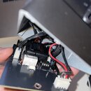 Fotografie zachycuje vnitřní elektroniku zařízení. Na černé desce je umístěn černý modul s nápisem „ELECTRONICS“ a „Op-Amp Low Noise“. Jsou vidět růz…