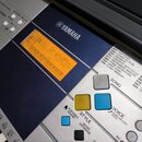 Detailní pohled na ovládací panel stříbrného digitálního klavíru značky YAMAHA. Oranžový displej zobrazuje nápis 001 GrandPno. Na panelu jsou viditel…