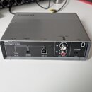 Šedý USB audio interface s nápisem UR12, USB AUDIO INTERFACE 24-bit / 192kHz D-PRE. Na zadní straně jsou konektory s popisky 5V DC, POWER SOURCE, USB…