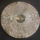 Kruhový činel z kovového materiálu s výrazně kovaným povrchem a koncentrickými rýhami. V centrální části je vidět nápis "Paiste" a číslo "9447". Povr…
