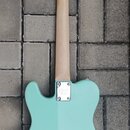 Zadní strana elektrické kytary s tyrkysovým trupem a světlým dřevěným hnedkem. Na kovové krytce krkovnice je viditelné logo "J&D Guitars". Povrch nás…