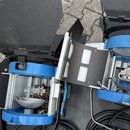 Dvě modré studiové reflektory s černými clony a stříbrnými kovovými vložkami. Uvnitř obou zařízení jsou vidět žárovky a odrazové plochy. Na přístrojí…