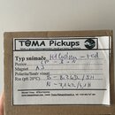 Fotografie znázorňuje hnědý kartonový krabič s nalepeným bílým štítkem. Na štítku je nápis TUMA Pickups a text Výroba a opravy elektromagnetických sn…