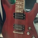 Elektrická kytara s červeně stínovaným trupem a hnedým hmatníkem. Nástroj má dva černých humbuckery, jeden tónový potenciometr a jeden přepínač. Na h…