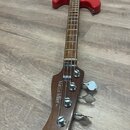 Čtyřstrunný basový kytara s červeným trupem a hnědým hmatníkem. Na hlavě nástroje je bílý nápis Marcus Miller P5 a logo Sire. Povrch nástroje vypadá…